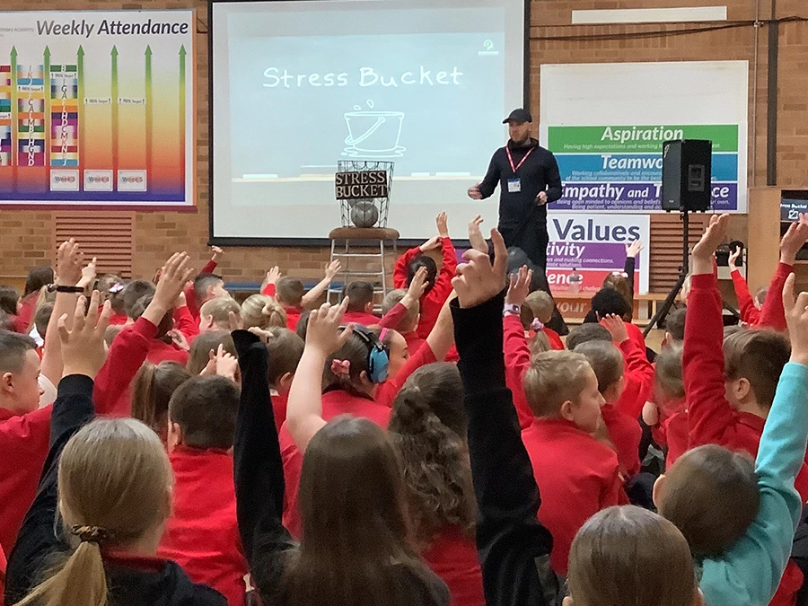 Oly Newton Run4YourMind public speaking at a school, talking about the concept of a stress bucket relating to mental health